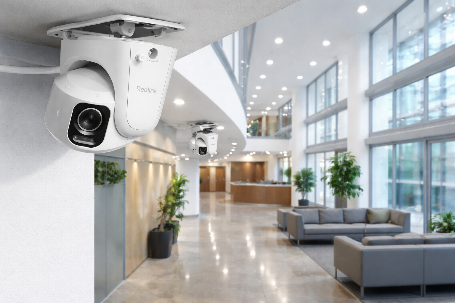 Security cameras in a modern office building lobby with large windows and a reception desk.